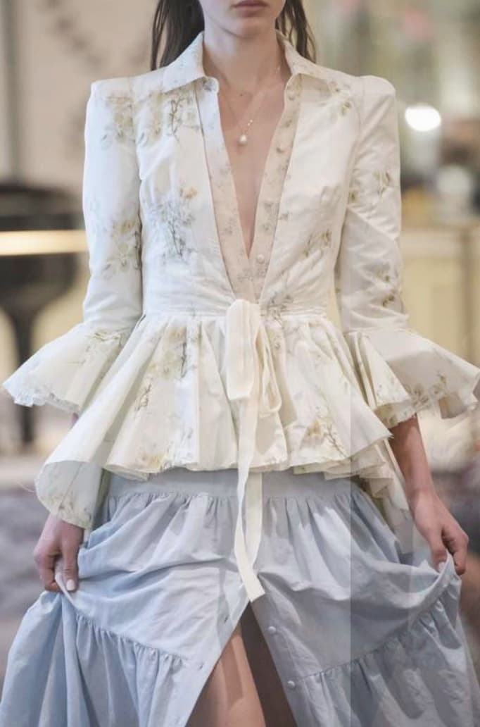 Model wearing a floral peplum blouse over a tiered skirt