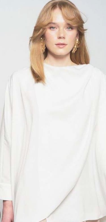 Model wearing a draped ivory blouse
